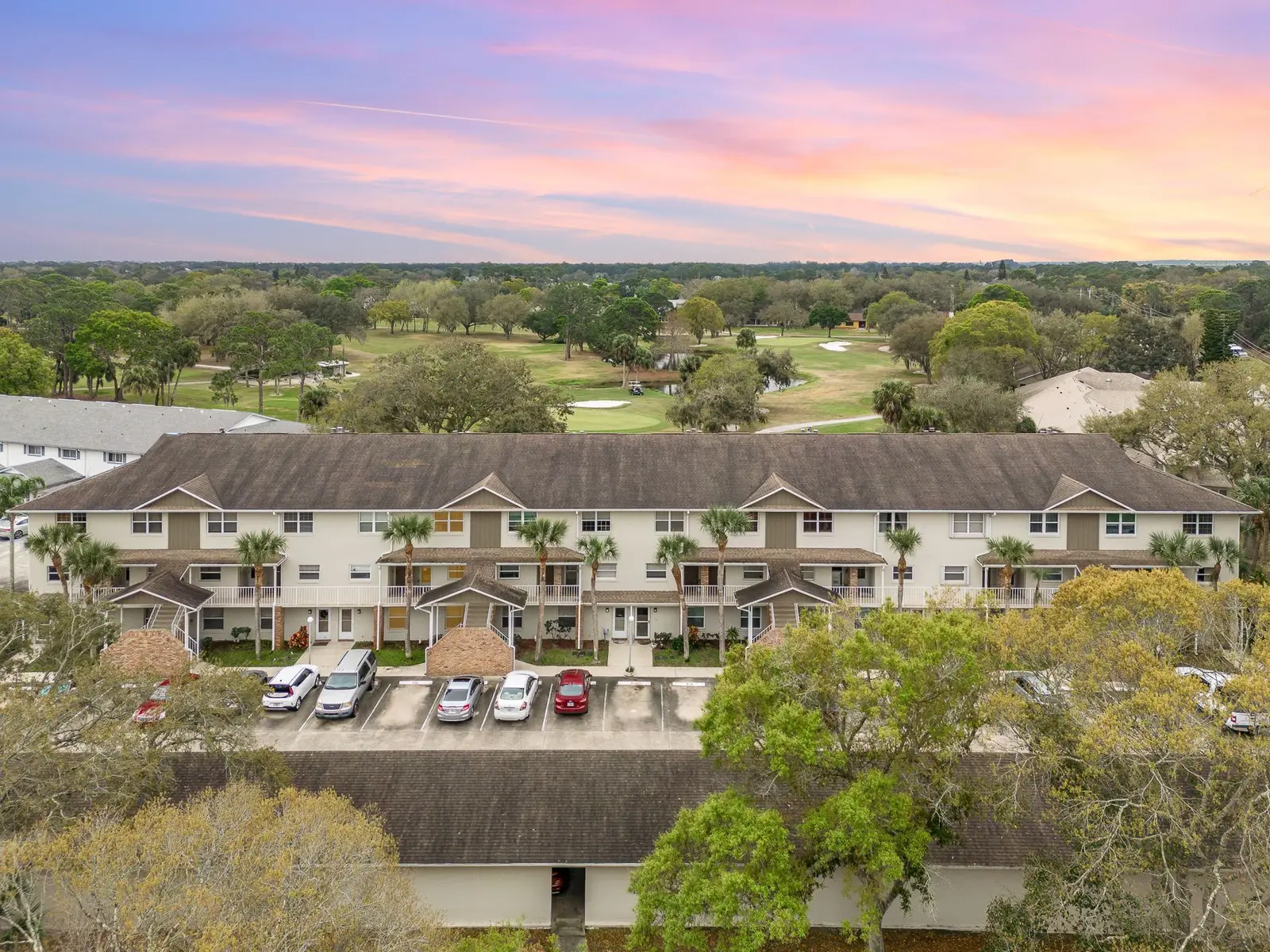 Aerial view of a townhome community beside a golf course at sunset