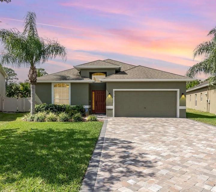 Residential exterior with a driveway and palm trees.